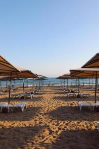 锡德Miramare Beach Hotel - Ultra All Inclusive的海滩上设有桌子和遮阳伞,还有大海