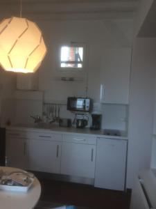 滨海图维列日落公寓的一间厨房,配有白色的橱柜和灯