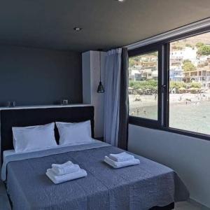 ParánimfoiSunrise Luxury Seaside Apartment的一间卧室配有一张床,上面有两条毛巾