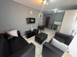 比勒陀利亚Beyond Comfort Apartment的客厅配有两张黑色沙发和一台电视机