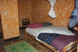 NyakinamaRed Rocks Rwanda - Campsite Guesthouse的小房间设有一张小床和枕头