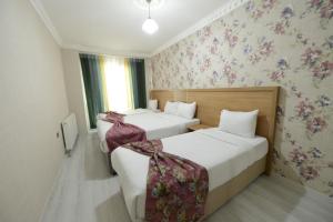 BostaniçiADA LİFE SUİT HOTEL VAN的两张位于酒店客房的床铺,配有花卉壁纸