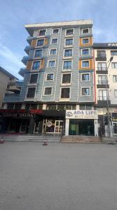 BostaniçiADA LİFE SUİT HOTEL VAN的一座高大的建筑,前面有一间商店
