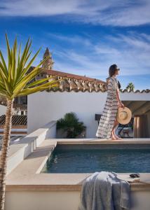 马略卡岛帕尔马波萨达特拉散塔精品酒店的一位女士在游泳池旁的房屋屋顶上行走