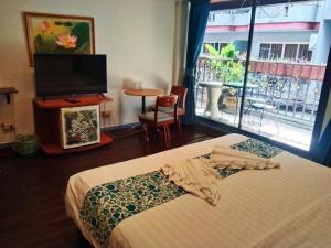 华欣the L Hua Hin的一间卧室设有一张床、一台电视和一个窗口。