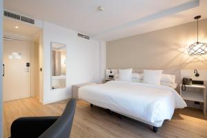 马贝拉Óbal Urban Hotel的白色卧室配有一张大床和椅子