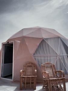 瓦迪拉姆RUM MAGiC lUXURY CAMP的两张藤椅和一个带桌子的帐篷