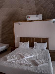 瓦迪拉姆RUM MAGiC lUXURY CAMP的一张带白色床单和枕头的床,上面有温度计