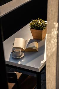 安塔利亚Verde Mare Hotels的一张桌子,上面放着一本书,还有一杯咖啡和植物