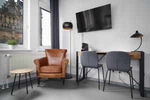 莱比锡Stylisches Studio im Herzen Leipzigs的一间设有三把椅子和一张书桌及电视的房间