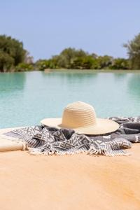 瑞塔尼Agua Green Resort的坐在沙滩上毛巾上的草帽