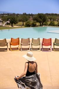 瑞塔尼Agua Green Resort的坐在椅子前的戴帽子的女人