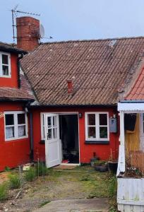 阿灵厄Rummeligt byhus i Allinge med værelse i stueplan og havkig的红色的房子,有白色门