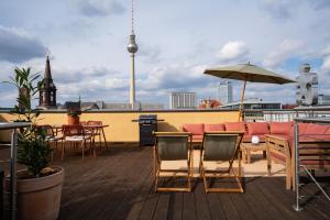 柏林The Charming by Curt Suites的屋顶甲板配有桌椅和遮阳伞