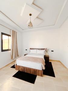 达赫拉Hotel Ahmed Ali的白色卧室配有一张床和一个吊灯