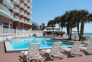 巴拿马城海滩Palmetto Beachfront Hotel, a By The Sea Resort的一个带白色椅子的游泳池以及大海