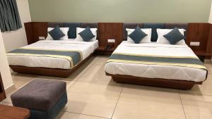 德奥加尔Hotel Omkareshwar Inn的一间卧室配有两张床和一张搁脚凳