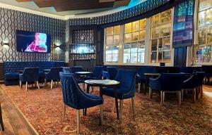 斯通Crown Hotel Stone的酒吧设有蓝色的桌椅和电视