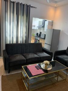 BrusubiThe Retreat Apartments的客厅配有黑色沙发和咖啡桌