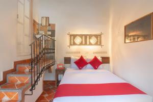 XicoOYO Hotel Coyopolan的一间卧室配有一张带红色枕头的床和楼梯