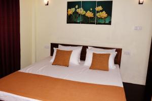 阿努拉德普勒Leaf Dew Resort的一间卧室配有带白色床单和橙色枕头的床。