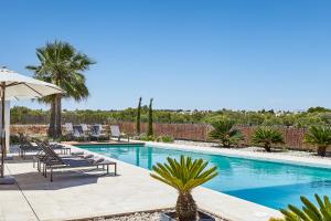 坎波斯Villa Es Trenc的游泳池配有躺椅和遮阳伞