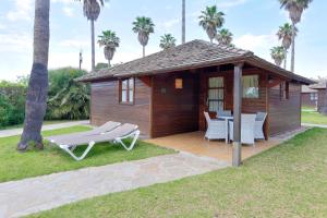 萨洛Camping & Resort Sangulí Salou的小屋配有桌椅和棕榈树
