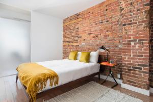 蒙特利尔Le Merrill Boutique Hotel的一间卧室设有砖墙和一张黄色枕头的床
