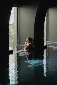蓬塔德尔加达NINE DOTS Azorean Art Boutique Hotel的坐在窗台上水中的女人