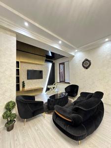 Yalanghoch253 ул.Паркентская Ташкент的客厅配有黑色皮革家具和平面电视