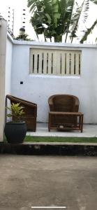 达累斯萨拉姆Jambo hostel tz的两把长椅,坐在白色墙前