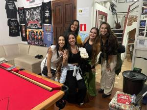 欧鲁普雷图La Musica Hostel OuroPreto的一群女孩站在桌子旁边,带有棒球棒