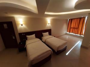 卡尔巴拉Coral Hotel Karbala的酒店客房设有两张床和窗户。