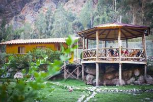 乌鲁班巴Eco Lodge Cabañas con Piscina的一座黄色的房子,在田野上设有甲板
