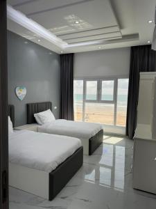 阿夏尔奇亚Sea View Chalet Al Ashkharah的卧室设有两张床,享有海滩美景