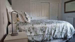 奥克兰Okura River Estate Getaway的一间卧室配有一张带白色毯子和灯的床。