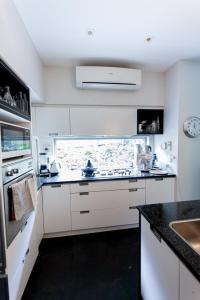 奥克兰Artist Photographers Home Studio的白色的厨房设有水槽和炉灶。