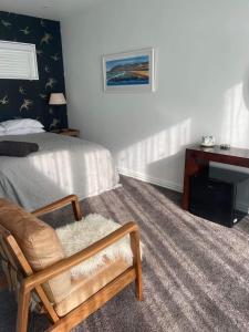 但尼丁Guest Suite St Clair Beach的一间卧室配有一张床、一把椅子和一张书桌