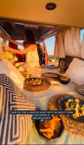 波尔蒂芒Rent a Blue Classics' s Campervan for your Road trip in Portimao -VOLKSWAGEN T3的坐在面包车后面的女人,带食物