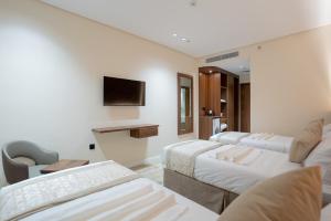 Ajyadفندق روحة المقام的酒店客房设有三张床和电视。