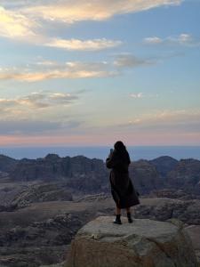 瓦迪穆萨Petra Desert Dream Hotel的站在岩石上,拍着沙漠照片的女人