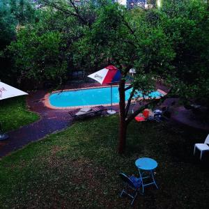 温特和克Hotel Pension Moni的游泳池旁的一棵树和两把椅子及一把遮阳伞