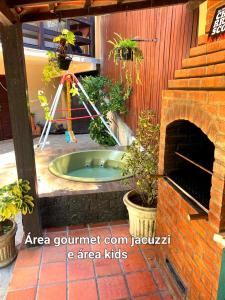 彼得罗波利斯Aconchego de Itaipava - Casa de 3 quartos, ampla, equipada, com área kids, jacuzzi, em meio a Natureza e próximo ao centro do bairro的植物庭院中间的热水浴池