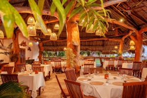 Ambondrona诺西贝酒店及水疗中心的餐厅拥有白色的桌椅和棕榈树