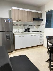 卡塔赫纳Apartamento cómodo cerca al aeropuerto的厨房配有白色橱柜和不锈钢冰箱