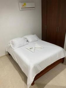 卡塔赫纳Apartamento cómodo cerca al aeropuerto的一张带白色床单的床和两张横线
