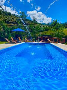 FazendinhaPousada Altitude 1200的一个大蓝色游泳池,背景是一座山