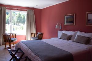 拉安戈斯图拉镇Hostería Las Semillas的一间卧室设有一张带红色墙壁的大床