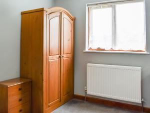 佩伦波斯Contention Barn的一间卧室设有木制橱柜和窗户。
