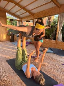潘泰莱里亚The Place Yoga Retreat *FREE YOGA CLASS的两个女人做瑜伽姿势,另一个女人站在她背上